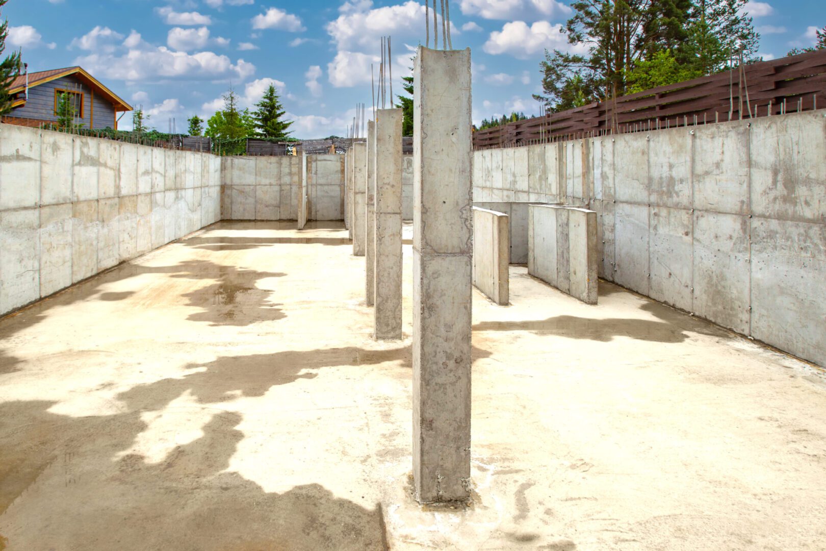 Concrete foundation with vertical pillars in a construction site under a clear sky.